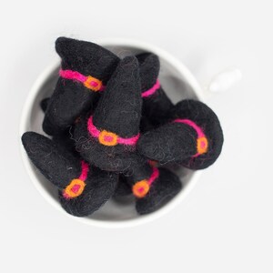 May include: A bowl filled with felt witch hats. The hats are black with pink and orange trim.