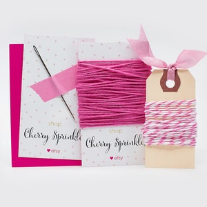 May include: A crafting set featuring pink thread, a needle, and a tag with pink and white twine. The set includes a pink card and two cards with the text "Cherry Sprinkle" and the Etsy logo.