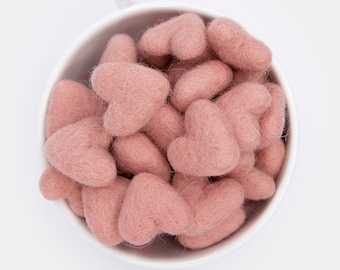 May include: A white ceramic cup filled with a large quantity of small, blush pink felt hearts.