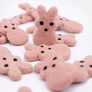 May include: A group of pink felt bunny shaped ornaments with black eyes and noses.