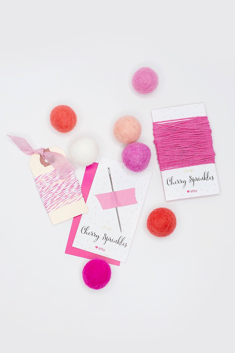 May include: A flat lay of pink and red felt balls, pink and white twine, and two cards that say "Shop Cherry Sprinkles" with an Etsy logo.