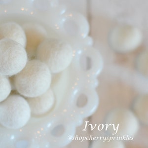 May include: Ivory wool balls in a white bowl. The balls are soft and fluffy, and they are perfect for adding a touch of whimsy to any room. @shopcherry sprinkles