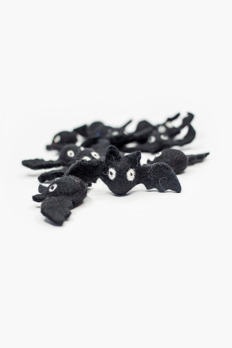 May include: A group of black felt bats with white eyes. The bats are arranged in a line, with the largest bat in the front.