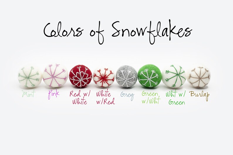 Puede incluir: Una fila de ocho adornos de fieltro con forma de copo de nieve, cada uno con un color y dise&ntilde;o diferente. Los colores son menta, rosa, rojo con blanco, blanco con rojo, gris, verde con blanco, blanco con verde y arpillera.