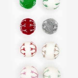 Puede incluir: Ocho adornos de fieltro en varios colores con dise&ntilde;os bordados en blanco. Los adornos son verdes, blancos, rojos, grises, blancos con bordados rojos, blancos con bordados marrones, blancos con bordados rosas y blancos con bordados verdes.