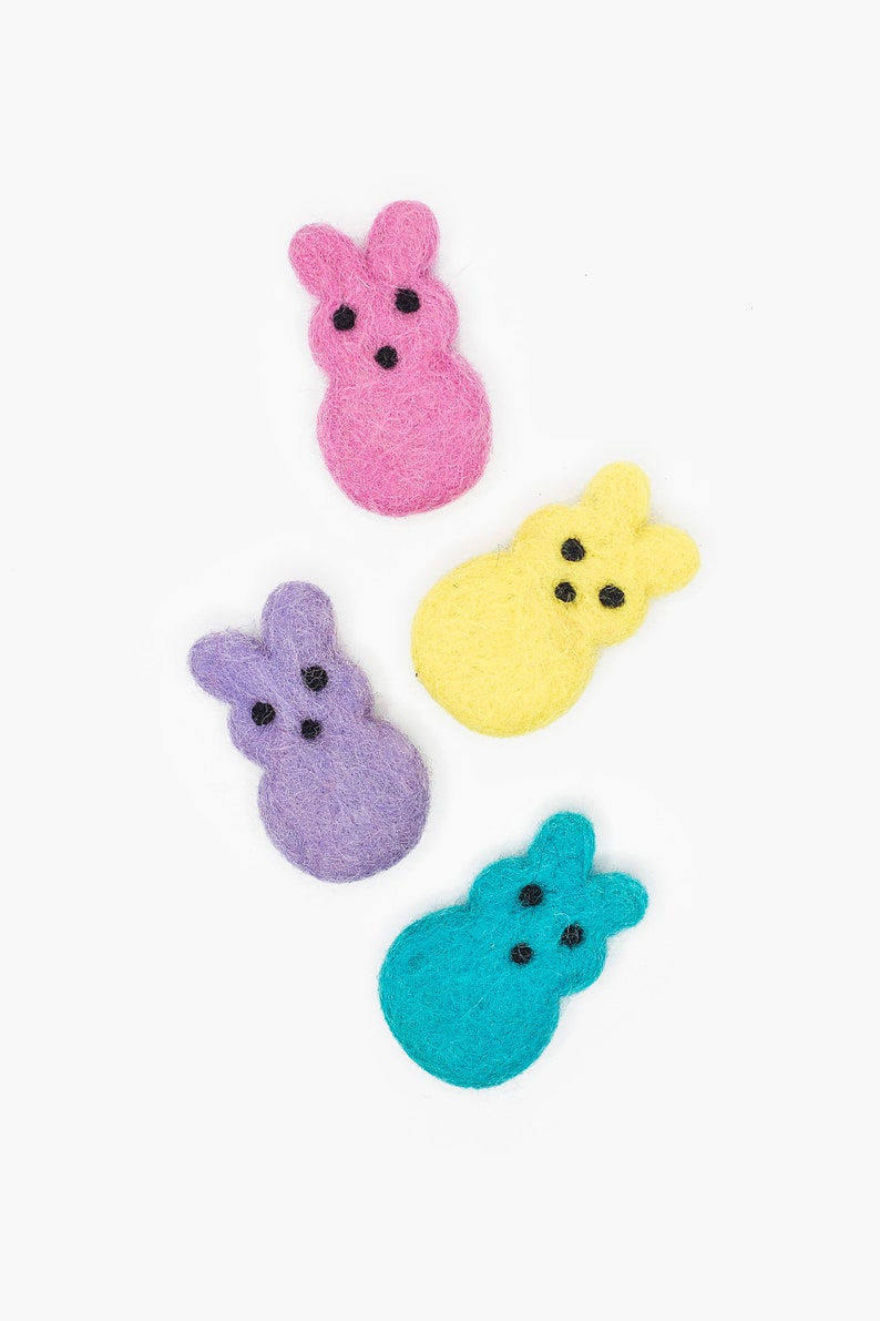 May include: Four felt Easter bunny shapes in different colors: pink, yellow, purple, and blue. Each bunny has black eyes.