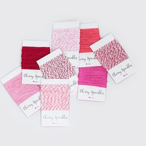May include: An assortment of colorful twine spools in shades of red and pink, including solid and two-tone options. Each spool is labeled with the text "Cherry Sprinkles" in a handwritten style font.