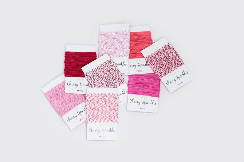 May include: An assortment of colorful twine spools in shades of red and pink, including solid and two-tone options. Each spool is labeled with the text "Cherry Sprinkles" in a handwritten style font.