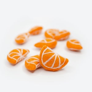 May include: A group of felt orange slices, some with white stitching, on a white background.