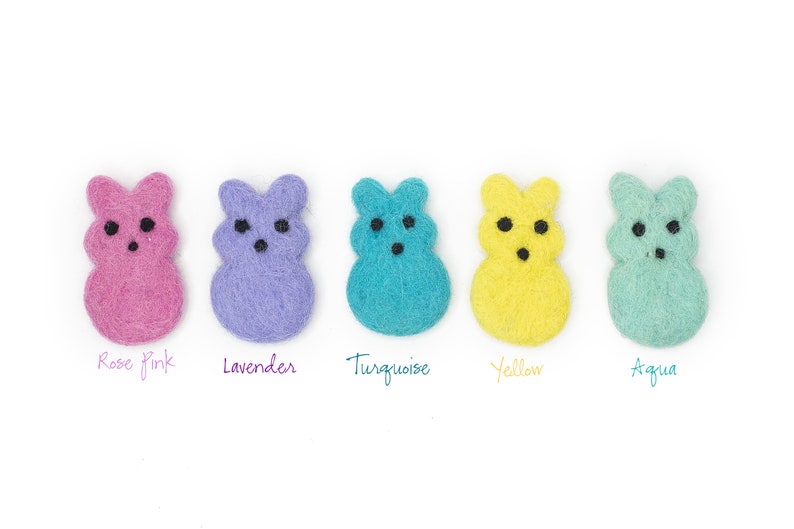 May include: Five felt bunny shapes in different colors: rose pink, lavender, turquoise, yellow, and aqua. Each bunny has black eyes and a simple, smiling expression.