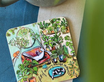 Könnte beinhalten: Ein quadratischer Untersetzer mit einer farbenfrohen Illustration eines weißen Kaninchens, das auf einem roten Sofa ein Buch liest, umgeben von zahlreichen grünen Topfpflanzen, einem schlafenden schwarz-weißen Hund und dem Text: Life is full of ordinary beautiful moments.