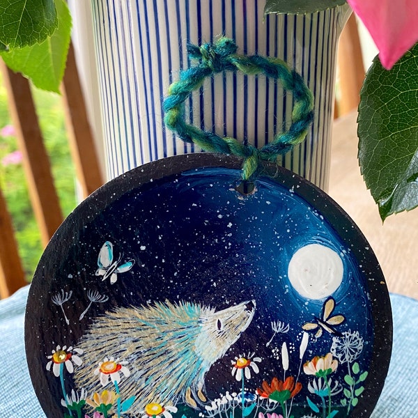 Hedgehog in colourful flower meadow with butterfly and full moon. Hand painted on 11cm round hanging slate.  Celebrating British wildlife.