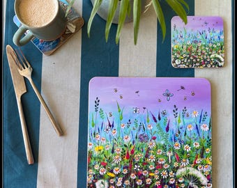 Könnte beinhalten: Ein quadratisches Platzset und ein passender quadratischer Untersetzer mit einer farbenfrohen Illustration einer Blumenwiese mit Gänseblümchen, bunten Blüten, Bienen und einem Schmetterling vor einem violett-blauen Himmel auf einem blau-weiß gestreiften Tischläufer.