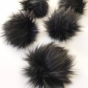 May include: Five black faux fur pom poms. The pom poms are fluffy and soft.