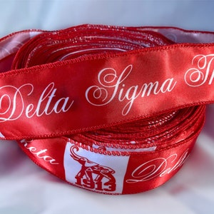 May include: Red satin ribbon with white lettering that reads "Delta Sigma Theta" and a white elephant logo with the year "1913" printed on it.
