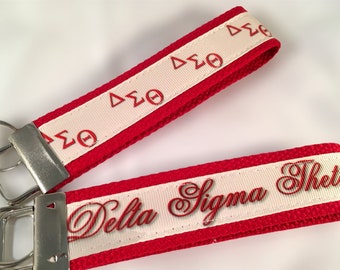May include: Red and white keychain with a white ribbon and red lettering that says "Delta Sigma Theta".