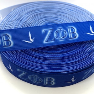 May include: A roll of blue ribbon with white lettering that reads "ZФB" and a white stylized bird design.
