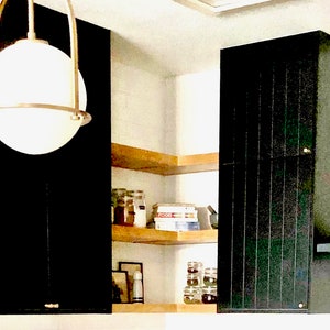 Puede incluir: Un armario de cocina negro con un estante de madera encima. El estante est&aacute; lleno de frascos y una caja con la etiqueta "FOOD".
