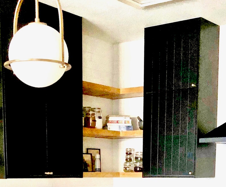 Puede incluir: Un armario de cocina negro con un estante de madera encima. El estante est&aacute; lleno de frascos y una caja con la etiqueta "FOOD".