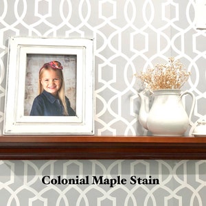 May include: A wooden shelf with a white frame picture of a young girl, a white teapot with dried flowers, and a white decorative object. The shelf is stained with a "Colonial Maple Stain" finish.