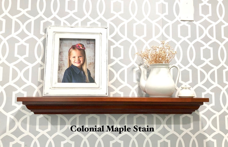 May include: A wooden shelf with a white frame picture of a young girl, a white teapot with dried flowers, and a white decorative object. The shelf is stained with a "Colonial Maple Stain" finish.