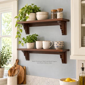 May include: Two dark brown wooden wall shelves with decorative corbel supports. The shelves hold potted green plants, beige bowls, glass spice jars, and white mugs. Text on the wall reads: Maple Farmhouse Shelf with Back Support with Perfect Brown Stain.