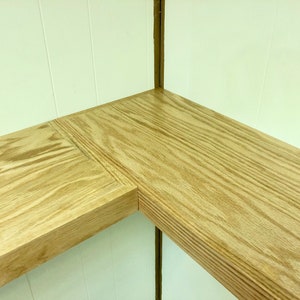 Puede incluir: Dos estantes de madera, uno en esquina y otro recto, est&aacute;n montados en una pared blanca. Los estantes son de madera marr&oacute;n claro con un patr&oacute;n de veta visible.