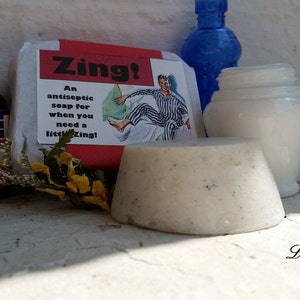 May include: A white bar of soap with a red and white label that reads "Zing! An antiseptic soap for when you need a little zing!" The label also features a cartoon illustration of a man in pajamas.