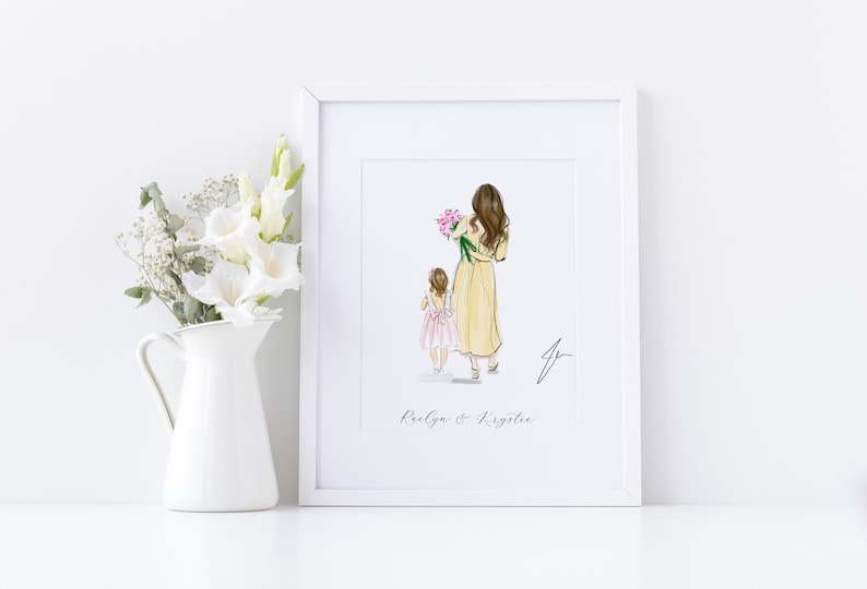 May include: A framed art print featuring a watercolor illustration of a woman and a child walking away, the woman holding pink flowers. The print is in a white frame, with the names "Raelyn & Krystee" below the image.