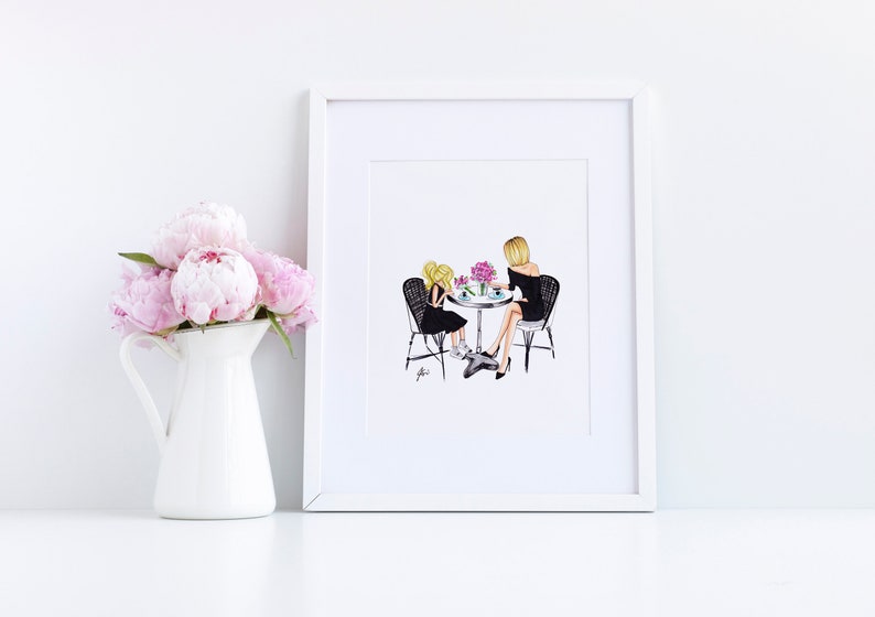 May include: A framed illustration of two people sitting at a table with flowers. The people are wearing black dresses and are looking at each other. The illustration is in a white frame.