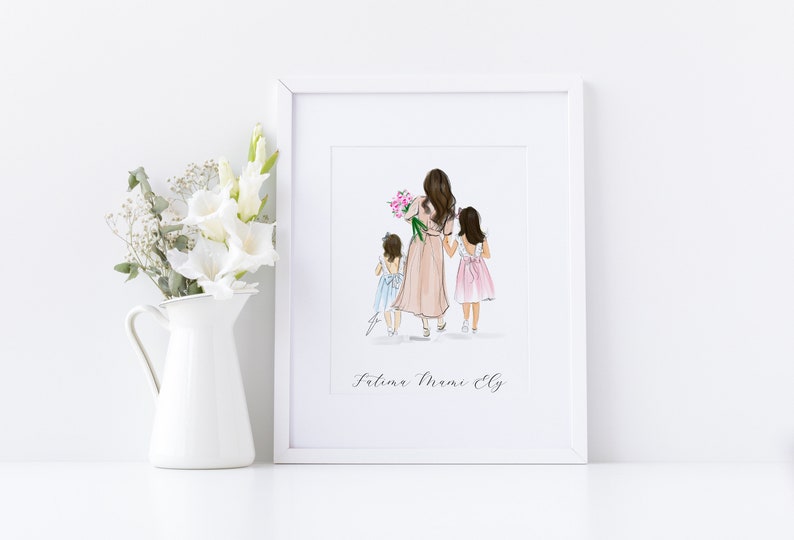 May include: A framed art print featuring a mother and two daughters walking away, holding hands. The mother wears a pink dress and carries flowers. The daughters wear a light blue and pink dress. The print is in a white frame.