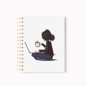May include: A spiral-bound notebook with a whimsical illustration of a person sitting cross-legged, working on a laptop and holding a coffee mug. The mug reads "Coffee First". The notebook has a white cover and gold spiral binding.