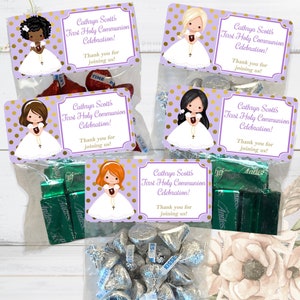 May include: Clear cellophane bags filled with candies, each topped with a purple label that reads "Cathryn Scott's First Holy Communion Celebration!" and features a cartoon girl. The bags contain chocolate kisses and Andes mints.