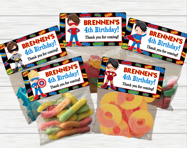 May include: Four favor bags with colorful candy and superhero themed labels. Each label says "Brennen's 4th Birthday! Thank you for coming!" with a different superhero character on each.