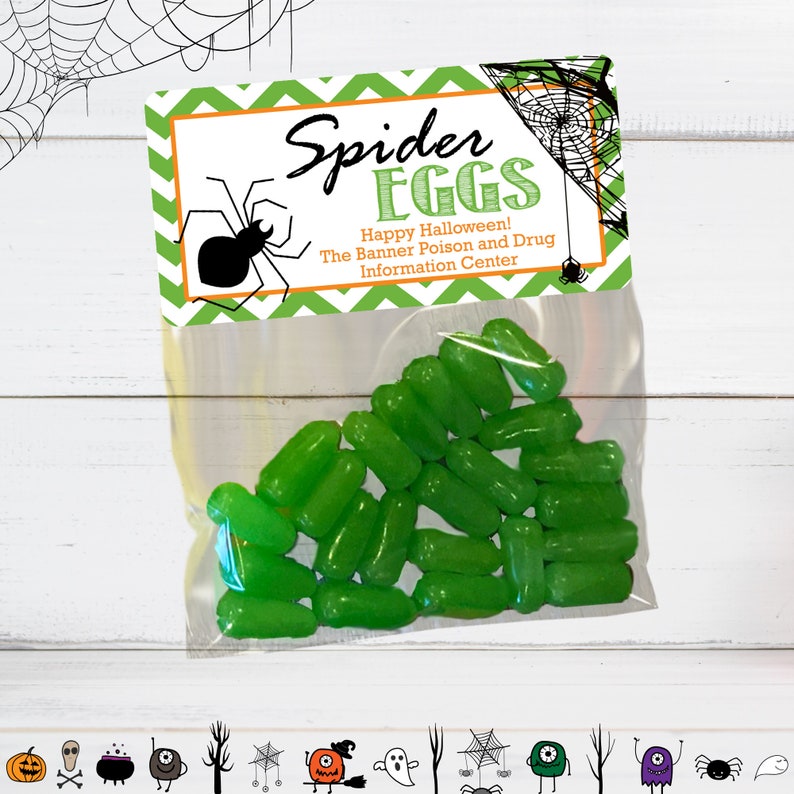 Puede incluir: Una bolsa de pl&aacute;stico transparente llena de dulces cil&iacute;ndricos de color verde brillante. La bolsa est&aacute; sellada con una tarjeta de cart&oacute;n con patr&oacute;n de chevr&oacute;n blanco y verde que presenta una ilustraci&oacute;n de una ara&ntilde;a negra, una telara&ntilde;a y el texto Spider EGGS Happy Halloween! The Banner Poison and Drug Information Center.