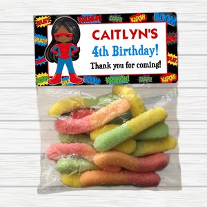May include: A superhero-themed birthday party favor bag with a black and red superhero character illustration, the text "CAITLYN'S 4th Birthday! Thank you for coming!" and a variety of colorful gummy worms.