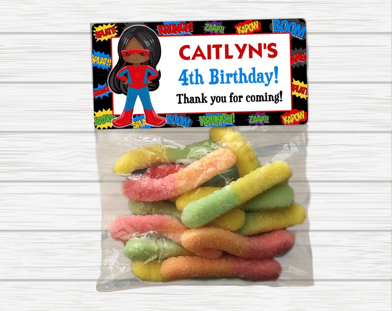 May include: A superhero-themed birthday party favor bag with a black and red superhero character illustration, the text "CAITLYN'S 4th Birthday! Thank you for coming!" and a variety of colorful gummy worms.
