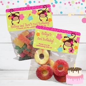 May include: Two favor bags with monkey themed birthday party labels. The bags are filled with colorful gummy candies. One bag has a label that says "Kaitlyn and Tara's 3rd Birthday! Thank you for celebrating with us!" The other bag has a label that says "Kaitlyn's 3rd Birthday! Thank you for celebrating with us!"