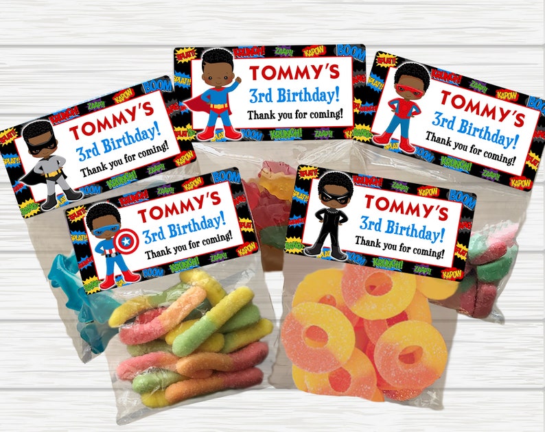 May include: Five small clear plastic bags filled with colorful candy. Each bag has a black and red superhero themed label with the text "TOMMY'S 3rd Birthday! Thank you for coming!"
