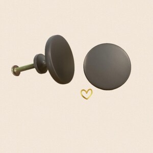 May include: Two round, matte black cabinet knobs with a screw for installation.