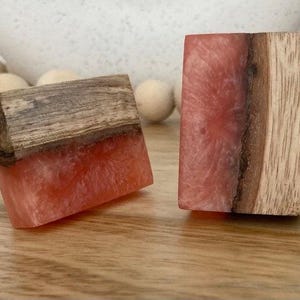 May include: Two rectangular wooden drawer pulls with a pink resin inlay. The pulls have a natural wood finish and a smooth, polished surface.