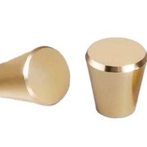 May include: Two gold-toned cabinet knobs with a round top and a tapered base.