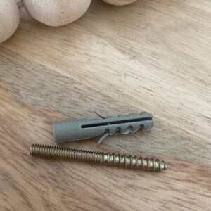 May include: A grey plastic drywall anchor with a screw. The anchor has a 6x9 marking on it. The screw is made of metal and has a gold finish.