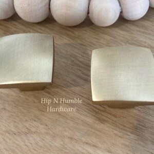 May include: Two brushed gold square cabinet knobs with rounded edges. Hip N Humble Hardware.