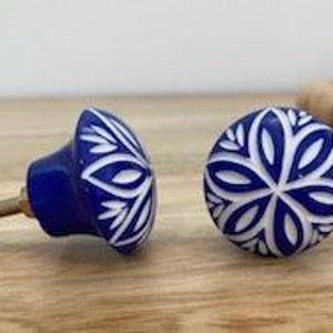 May include: Two blue and white ceramic cabinet knobs with a floral design. The knobs have a white floral pattern on a blue background.
