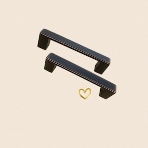 May include: Two black cabinet pulls with a brushed nickel finish. The pulls are rectangular in shape with rounded edges.
