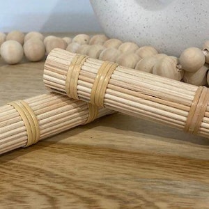 May include: Two natural woven bamboo placemats, rolled up and stacked on top of each other. The placemats are made of thin, light brown bamboo strips woven together.