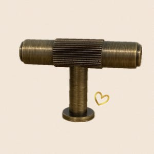 May include: A T-shaped cabinet knob with a textured, antique brass finish. The knob has a round base and a cylindrical stem.