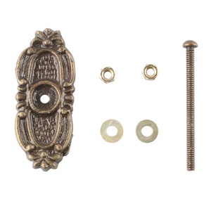 May include: A set of antique brass hardware for a door or cabinet. The set includes a decorative plate, a screw, two washers, and two nuts.