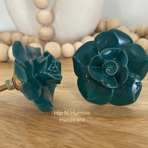 May include: Two teal blue ceramic rose-shaped drawer pulls with gold metal hardware.  Hip N Humble Hardware.